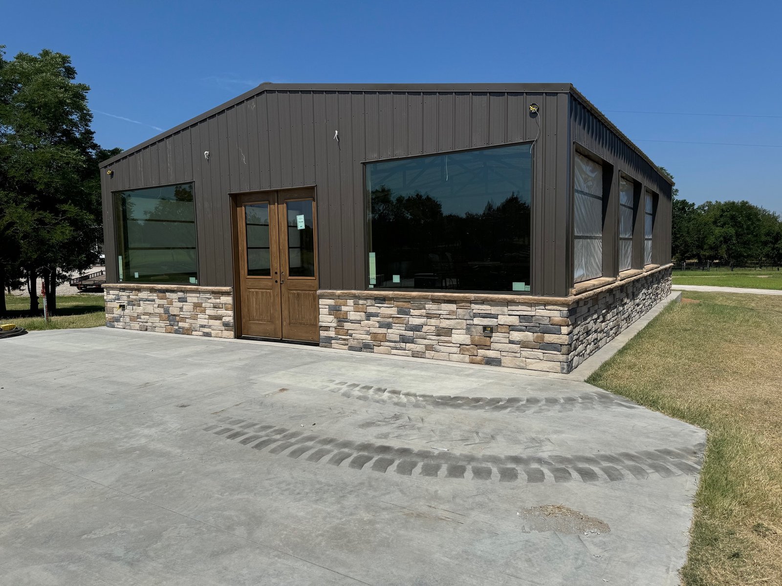 Exterior of the Persimmon Creek cabana with dark metal siding, stone wainscot and large windows
