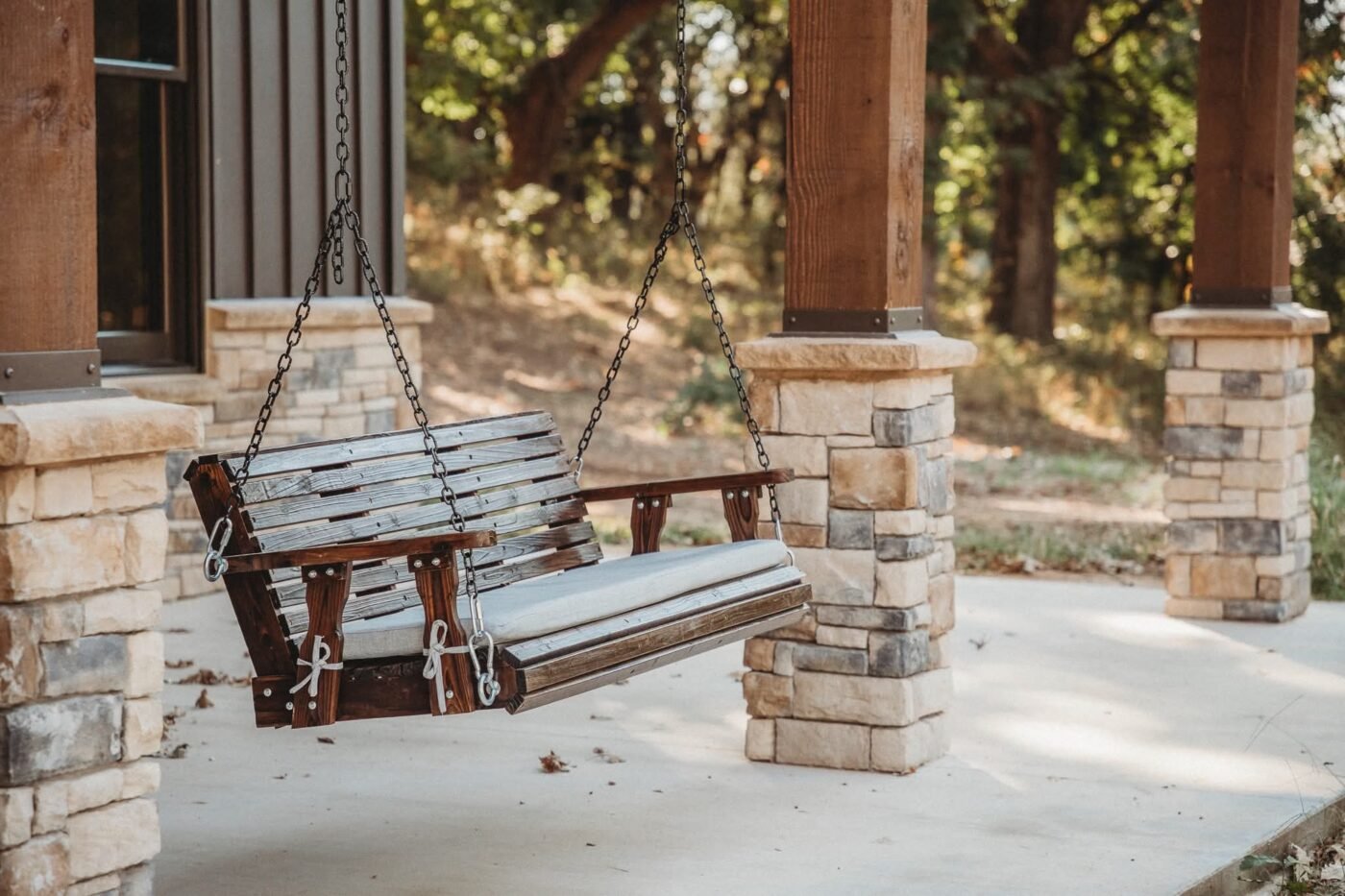 Porch swing hanging between stone and timber columns at Persimmon Creek Lodge