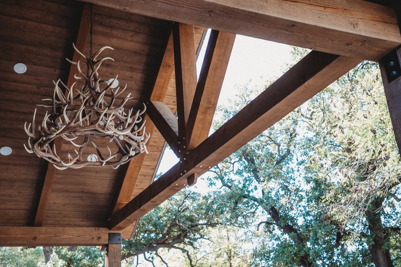 Exterior of the porch ceiling showing large timbers and antler chandelier